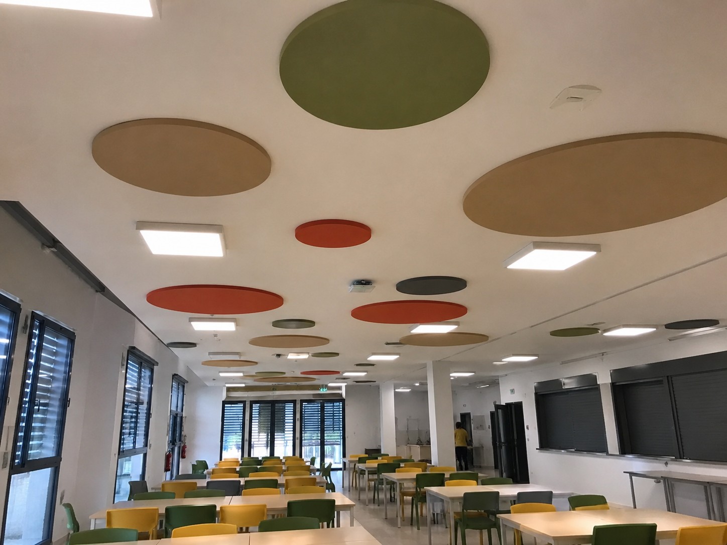 Comedor escolar con absorbentes ac&uacute;sticos circulares de colores en el techo