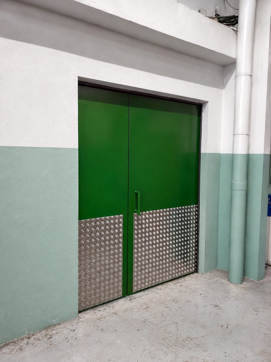 Puerta acústica doble industrial pintada en verde con chapa estriada inferior — SILENOR
